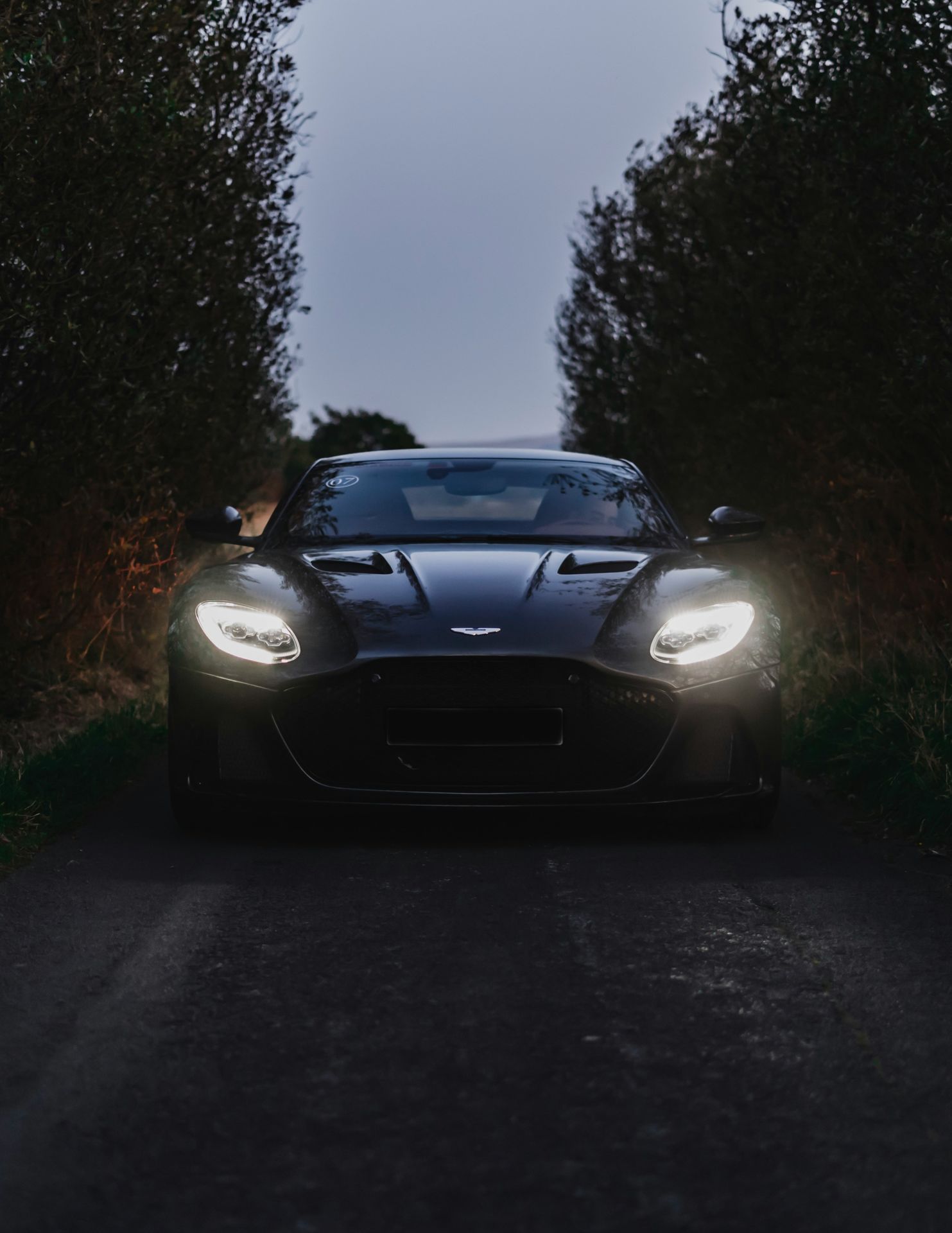 Aston Martin de nuit, phares allumés